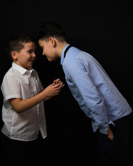 Two boys on a black background are brothers.Senior and junior.Atelier.Reproach