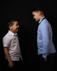 Two boys on a black background are brothers.Senior and junior.Atelier.The younger one laughs at the older one