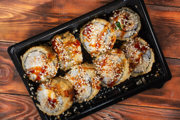 sushi in a black plastic container on a wooden background