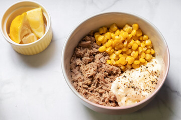 Preparing healthy sandwiches; tuna, corn, lemon and vegetables on marble cutting board. Top view