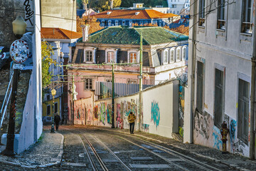 Alfama district narrow typical street view with rail. Lisbon, Portugal