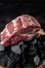 A piece of raw pork on the coals close-up