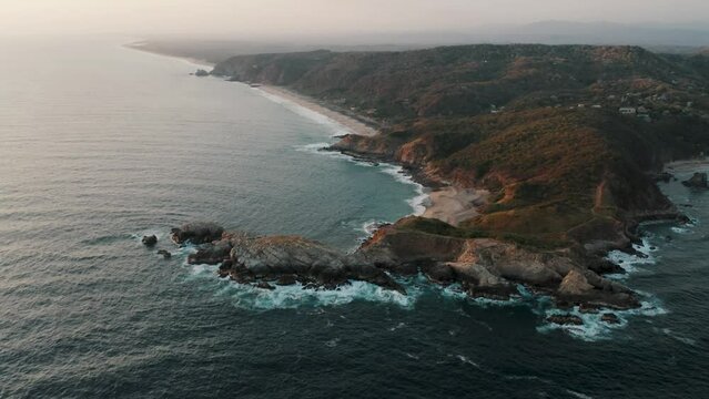 Rocky Coastline Of Punta Cometa Peninsula With Playa Mermejita And Playa La Ventanilla In The Distance In Mazunte, Mexico. - aerial tilt up