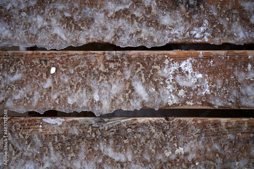 Poster fragment of an old frozen wooden fence with snow flakes adhered to. the wood structure is visible on