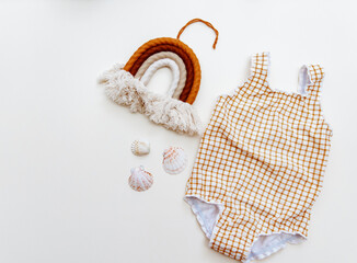 Summer kid's vacation concept - swimsuit on neutral beige background, minimal holiday  fashion baby. Top view, flat lay