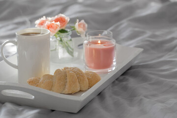 cup of coffee with croissant  and pink roses on bed in  bedroom