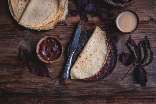 Crepes with chocolate spread on a rustic wooden background