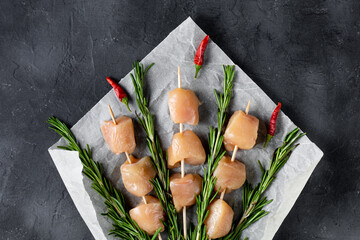 Raw chicken kebabs and rosemary in the form of a bouquet on a dark background.