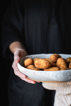 Potato croquettes being held by a woman in a black top, with copy space