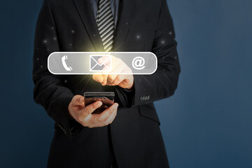 Businessman holding smart phone with business contact icons include mail telephone and address.