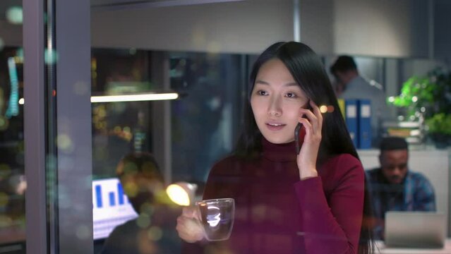 Young asian businesswoman standing in office, watching the modern city night view
