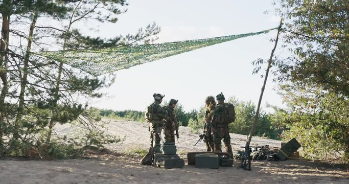Soldiers go out into field from military base where they leave crates of equipment, in search of the enemy, dressed in uniforms, with long weapons on their shoulders perform missions, actions