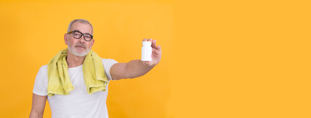 Senior man with pills. Senior man with bottle of supplement at fitness studio. People, sport and health care concept.