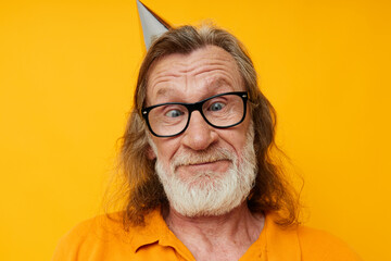 cheerful elderly man in glasses with a cap on his head yellow background