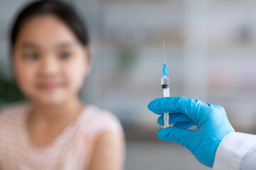Unrecognizable doctor making vaccination for asian child
