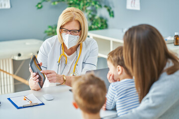 Pediatrician doctor examining little kids in clinic