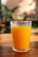 Glass of fresh orange juice on wooden table.