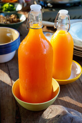 Glass bottles of fresh orange juice on wooden table.