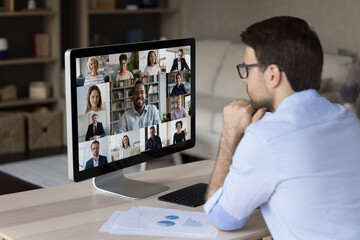 Focused young businessman holding video conference call with motivated diverse colleagues and African American male team leader, discussing working issues or negotiating project results remotely.