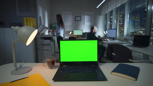 Laptop with green screen on desk in modern office downtown