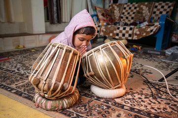 a small child trying to learning to play the tabla .
