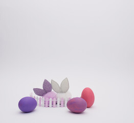 Colorful Bunnies and Easter eggs behind the fence on white background. Easter Holiday minimal concept.