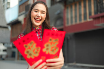 Beautiful Asian woman wearing a traditional red cheongsam on Chinese New Year.Hand holding red envelope or Ang pao with Chinese character means happiness or good fortune.