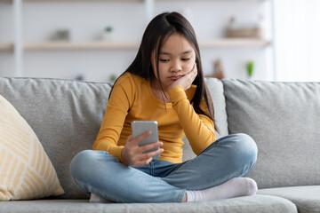 Bored teenager japanese girl using mobile phone at home