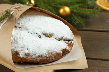 Wrapped Christmas Stollen with decoration on wooden table, closeup