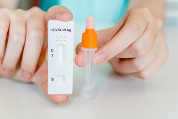 Hands holding Covid-19 rapid antigen test kit ready to use. Tube and test cassette with specimen