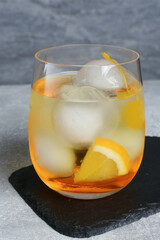 Delicious cocktail with orange, yellow cherry and ice balls on grey table