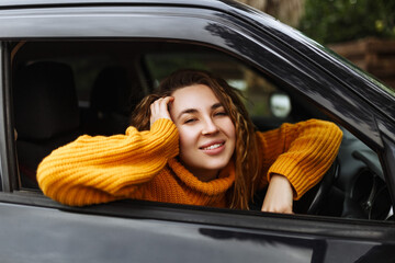 Portrait of young beautiful woman in yellow sweater sitting in the car.