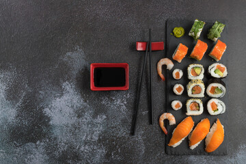 Delicious assorted sushi set with chopsticks and soy sauce on a  stone board.