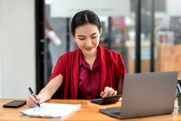 Confident young Asian businesswoman sitting working at her workplace at modern office.