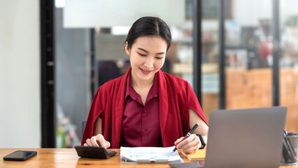 Fototapeta premium Confident young Asian businesswoman sitting working at her workplace at modern office.