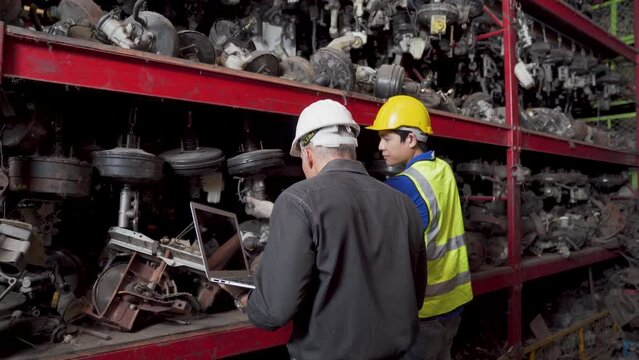 Worker and Foreman using laptop computer at a automotive spare parts warehouse.