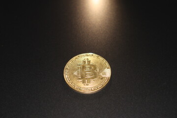 bitcoin coin on black background backlit with warm light 