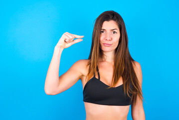 Upset Young beautiful sportswoman doing sport wearing sportswear over blue background shapes little...