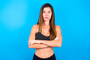 Fototapeta premium Picture of angry Young beautiful sportswoman doing sport wearing sportswear over blue background looking camera.