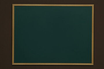 Clean green chalkboard hanging on brown wall