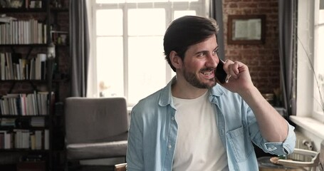 Millennial guy holding telephone talk from home discuss business with partner chat with friend then ending conversation saying goodbye finishing call. Young man speak on phone hold gadget close to ear