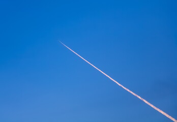 The trail from the flying plane on a blue sky