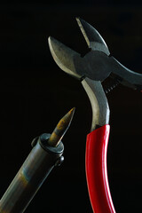 wire cutters and soldering iron. dark background close-up