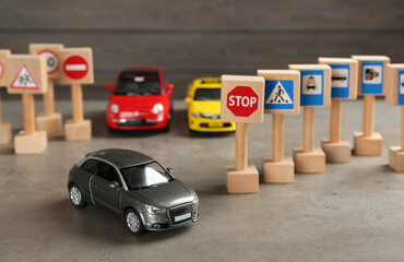 Many different miniature road signs and cars on grey table. Driving school