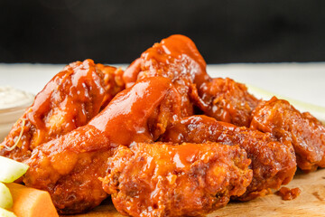 Lots of fried chicken wings covered in sauce. Buffalo wings.