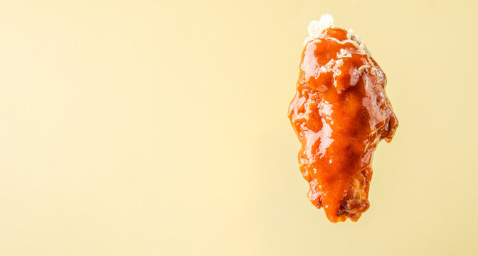A piece of fried wing in red buffalo sauce on a bright background, Banner, free space. Wing bbq