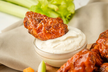 A piece of buffalo chicken wing in white blue cheese sauce, close-up.