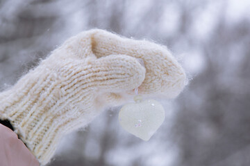 Woman holding white heart on winter snow background, close up. Valentines Day concept