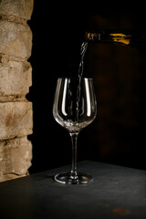 Dark bottle fills elegant crystal champagne flute with sparkling champagne with bubbles