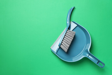 Plastic hand broom and scoop on green background, flat lay. Space for text - obrazy, fototapety, plakaty